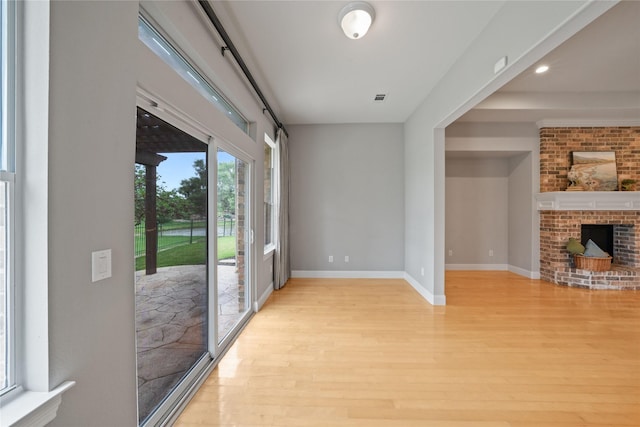 interior space featuring light wood finished floors, a fireplace, recessed lighting, baseboards, and visible vents