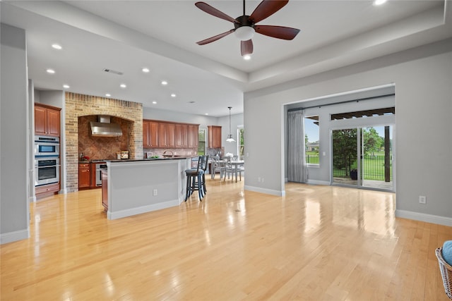 kitchen featuring wall chimney range hood, recessed lighting, ceiling fan, and decorative backsplash