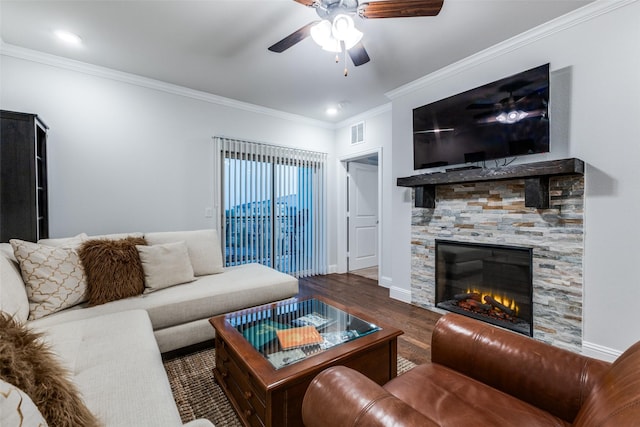 living area featuring a ceiling fan, visible vents, crown molding, wood finished floors, and a glass covered fireplace