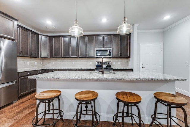 kitchen with decorative light fixtures, dark brown cabinetry, appliances with stainless steel finishes, and tasteful backsplash