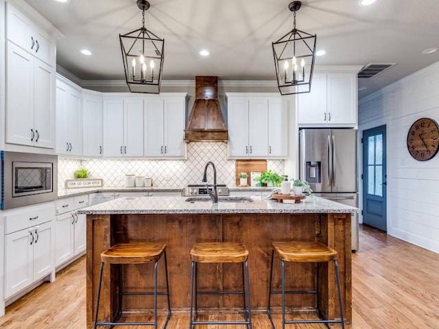 kitchen with a sink, premium range hood, stainless steel appliances, and a chandelier