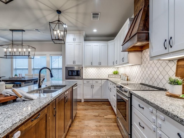 kitchen featuring visible vents, custom exhaust hood, a chandelier, a sink, and appliances with stainless steel finishes