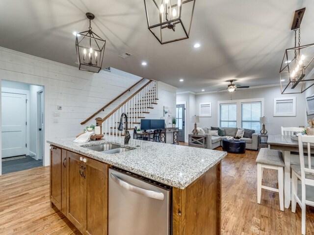 kitchen featuring stainless steel dishwasher, a sink, light wood finished floors, and brown cabinets