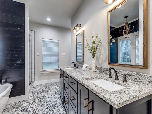 full bath with baseboards, double vanity, a freestanding tub, and a sink