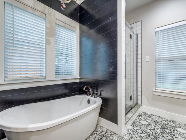 bathroom with baseboards, a freestanding tub, tile patterned flooring, and a stall shower