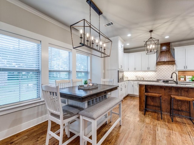 dining room featuring visible vents, light wood finished floors, plenty of natural light, and a notable chandelier