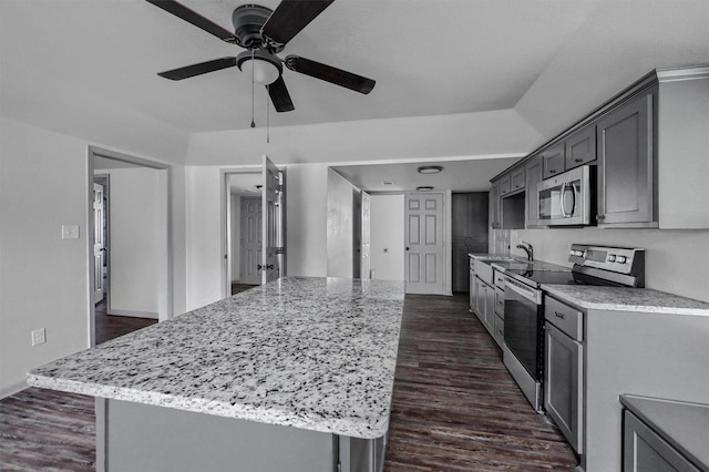 kitchen featuring a ceiling fan, a center island, dark wood-type flooring, a sink, and stainless steel appliances
