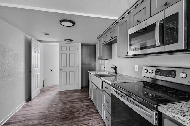 kitchen featuring visible vents, dark wood-type flooring, a sink, gray cabinetry, and stainless steel appliances