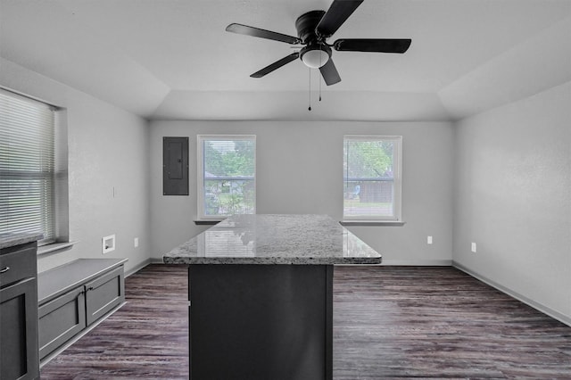 kitchen featuring light stone counters, a ceiling fan, a kitchen island, dark wood-style floors, and electric panel