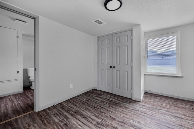 unfurnished bedroom featuring baseboards, visible vents, wood finished floors, and a closet