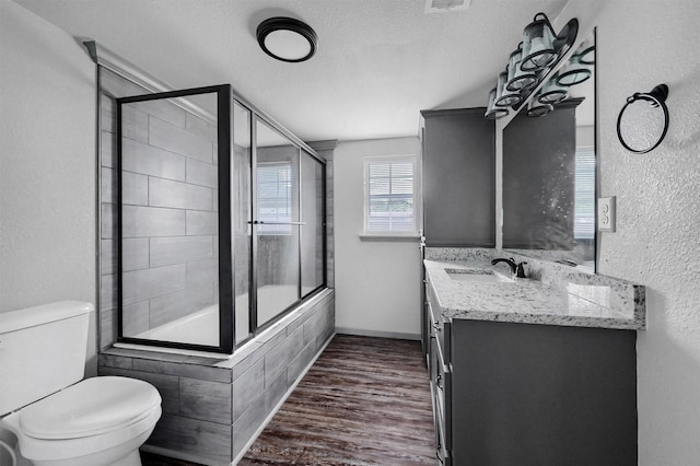 bathroom featuring a textured wall, vanity, toilet, a textured ceiling, and wood finished floors