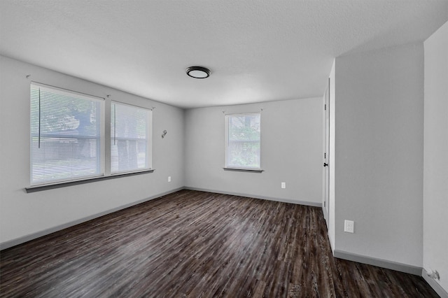 empty room featuring baseboards, a textured ceiling, and dark wood-type flooring