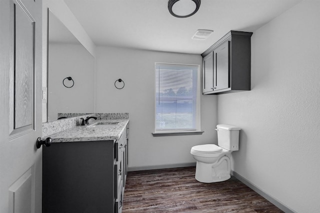bathroom featuring visible vents, wood finished floors, vanity, baseboards, and toilet