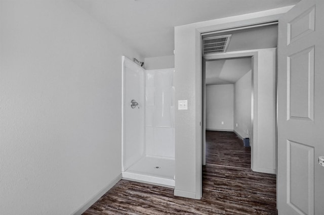 bathroom with a shower, baseboards, wood finished floors, and visible vents