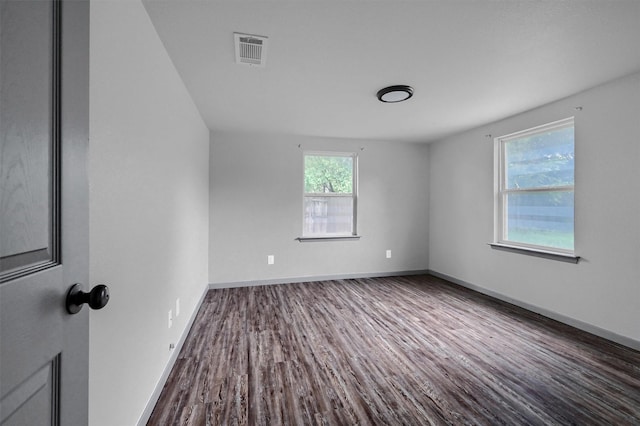 spare room with baseboards, visible vents, and dark wood-type flooring