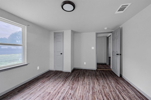 unfurnished bedroom with baseboards, wood finished floors, and visible vents