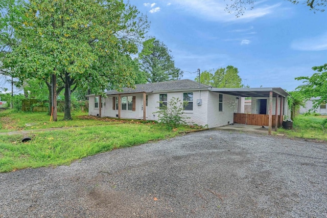ranch-style house featuring brick siding, a front lawn, driveway, and an attached carport