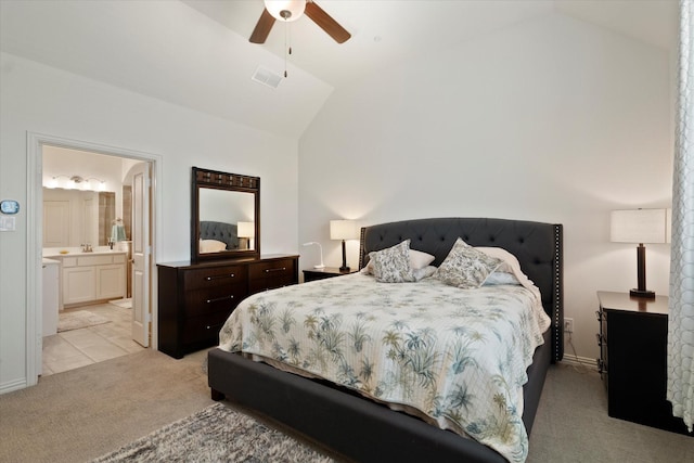 bedroom featuring visible vents, lofted ceiling, light carpet, a sink, and ensuite bath