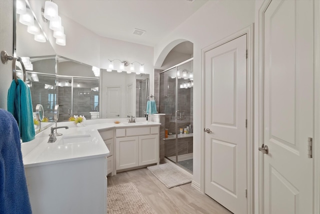 bathroom with visible vents, a shower stall, wood finished floors, and vanity