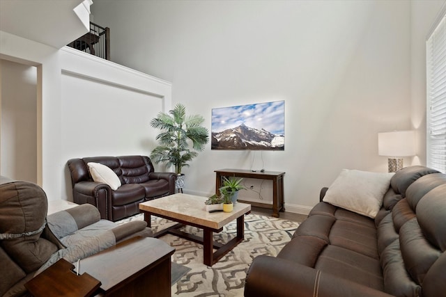 living room featuring baseboards, light wood finished floors, and a towering ceiling