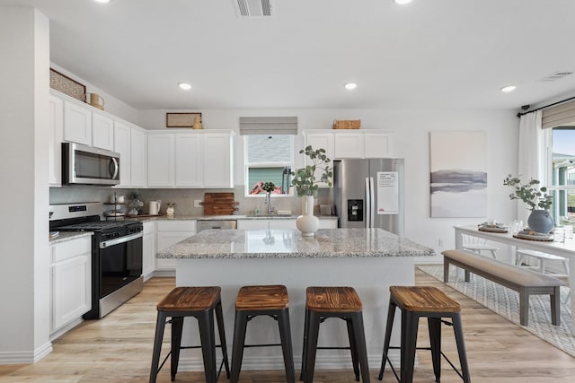 kitchen with visible vents, a kitchen breakfast bar, white cabinets, and stainless steel appliances