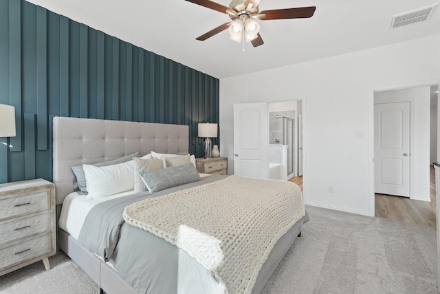 bedroom featuring visible vents, a ceiling fan, baseboards, carpet flooring, and ensuite bath