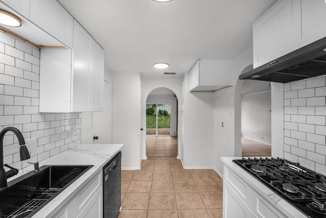 kitchen with arched walkways, a sink, black appliances, and white cabinets