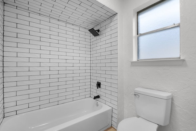 bathroom with shower / bath combination, a textured wall, and toilet