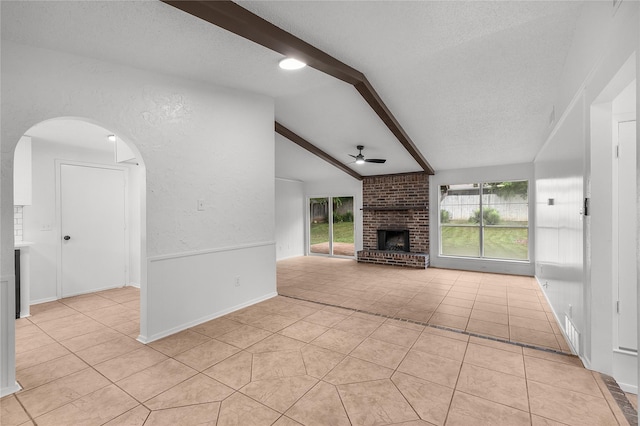 unfurnished living room featuring a brick fireplace, a textured ceiling, ceiling fan, and light tile patterned floors