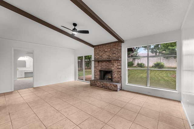 unfurnished living room featuring a brick fireplace, light tile patterned flooring, ceiling fan, plenty of natural light, and lofted ceiling with beams