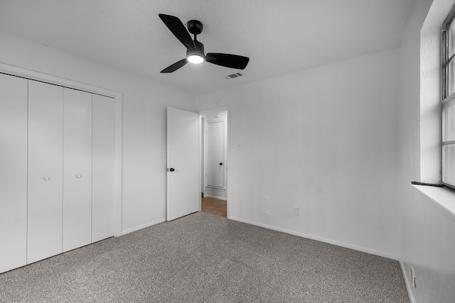 unfurnished bedroom featuring carpet flooring, a ceiling fan, baseboards, visible vents, and a closet