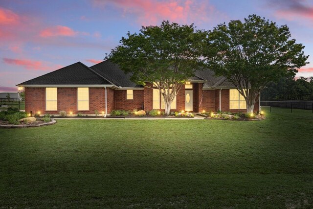 view of front facade featuring a lawn, brick siding, and fence