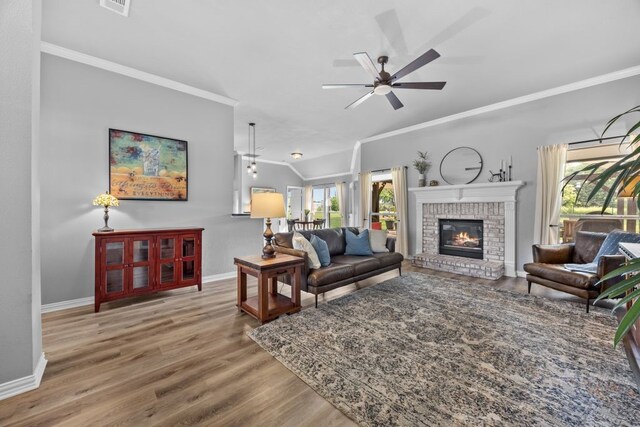 living room featuring crown molding, wood finished floors, baseboards, a ceiling fan, and vaulted ceiling