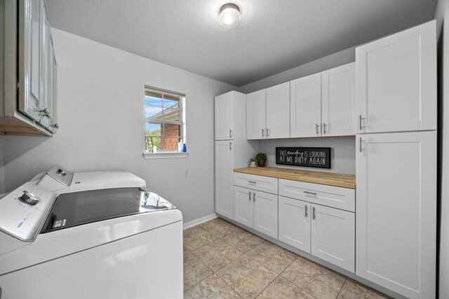 clothes washing area with independent washer and dryer, baseboards, and cabinet space