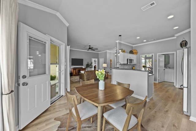 dining room with crown molding, visible vents, and light wood-type flooring