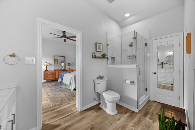 bathroom with toilet, a ceiling fan, wood finished floors, and a stall shower