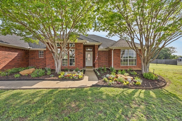 view of front of home with brick siding, fence, and a front yard