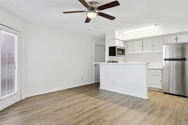 kitchen with stainless steel appliances, a textured ceiling, and light wood-type flooring