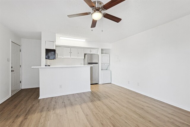 kitchen with freestanding refrigerator, light wood-type flooring, light countertops, white cabinets, and a ceiling fan