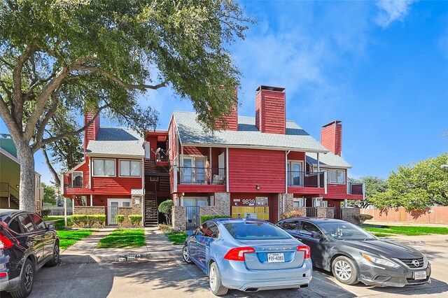 view of property with uncovered parking and stairway