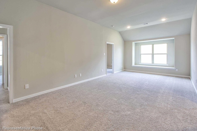 spare room featuring baseboards, carpet, and vaulted ceiling