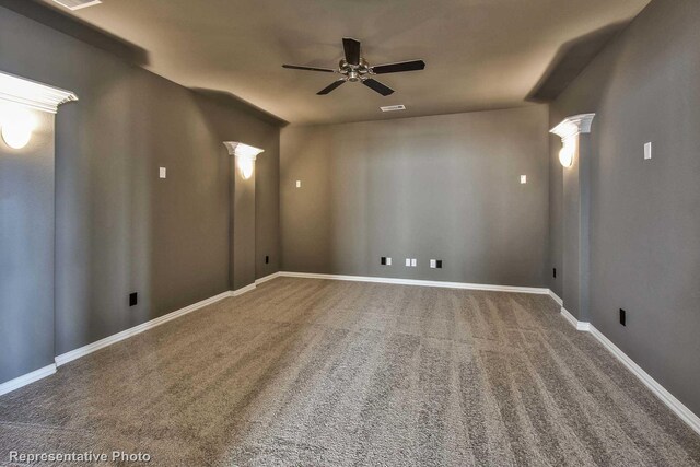 carpeted empty room featuring baseboards, a ceiling fan, decorative columns, and visible vents