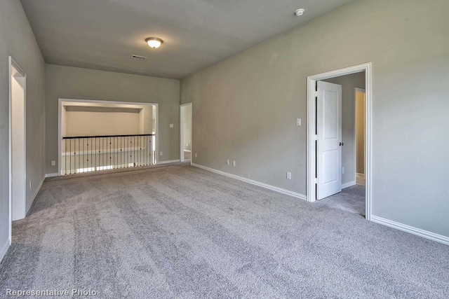 spare room with carpet floors, baseboards, and visible vents