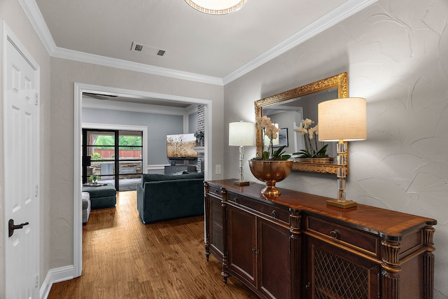 hallway with visible vents, crown molding, and wood finished floors