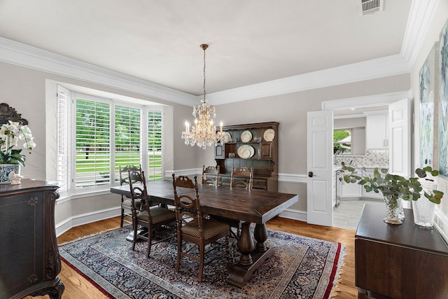 dining room featuring crown molding, visible vents, an inviting chandelier, and light wood finished floors