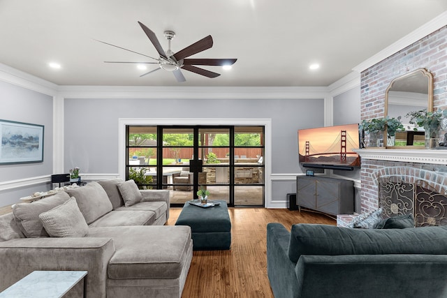 living area featuring crown molding, a ceiling fan, wood finished floors, and a fireplace