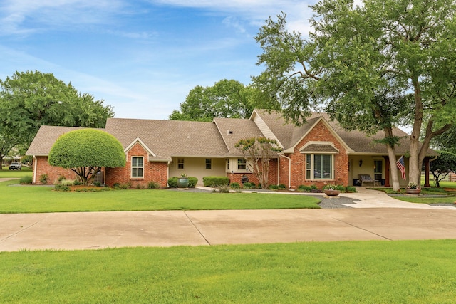 ranch-style home featuring brick siding, a shingled roof, and a front yard