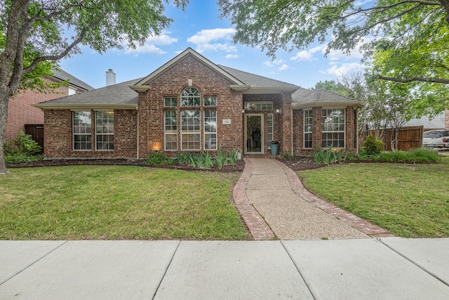 view of front of home with fence, a front lawn, and brick siding