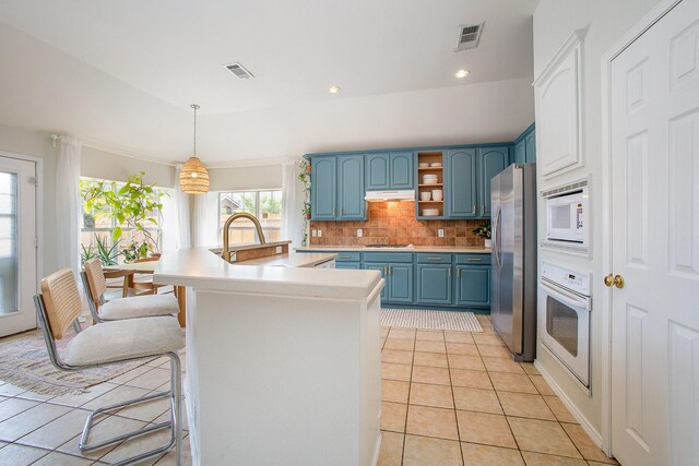kitchen featuring decorative backsplash, blue cabinetry, visible vents, appliances with stainless steel finishes, and light tile patterned floors