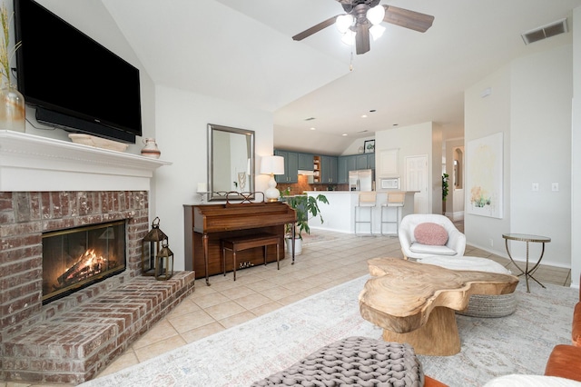 living room with a fireplace, a ceiling fan, light tile patterned floors, lofted ceiling, and visible vents